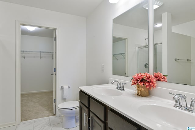 bathroom featuring vanity, a shower with shower door, and toilet