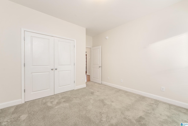 unfurnished bedroom featuring light colored carpet and a closet