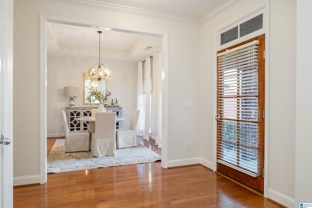 unfurnished dining area featuring a raised ceiling, wood-type flooring, a healthy amount of sunlight, and a chandelier