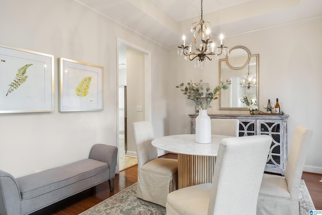 dining space with an inviting chandelier, ornamental molding, a tray ceiling, and hardwood / wood-style floors