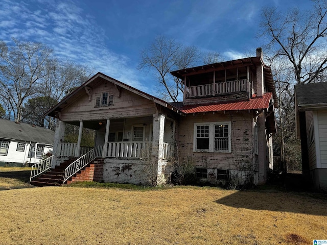 view of front of home featuring a front yard, a balcony, and covered porch