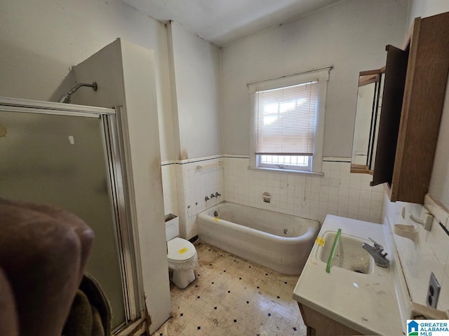 full bathroom with vanity, toilet, separate shower and tub, and tile walls