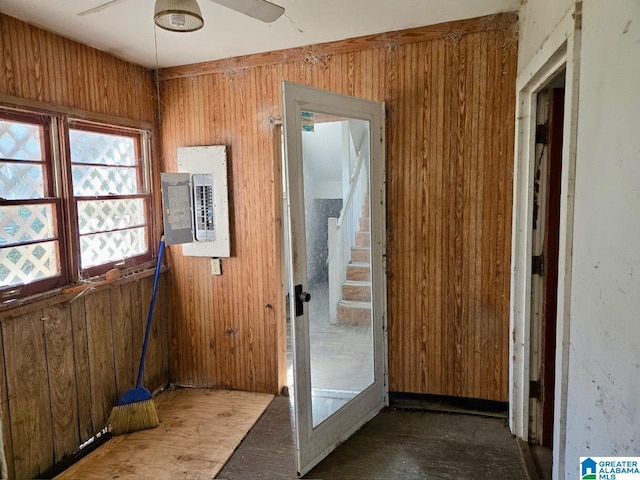 doorway to outside with ceiling fan, wooden walls, and electric panel