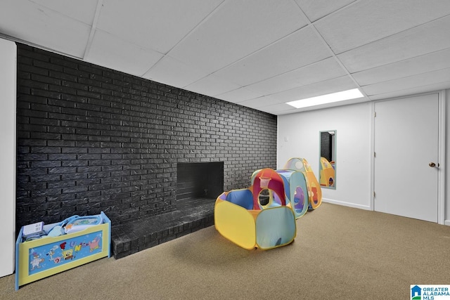 rec room with a drop ceiling, a brick fireplace, brick wall, and carpet flooring