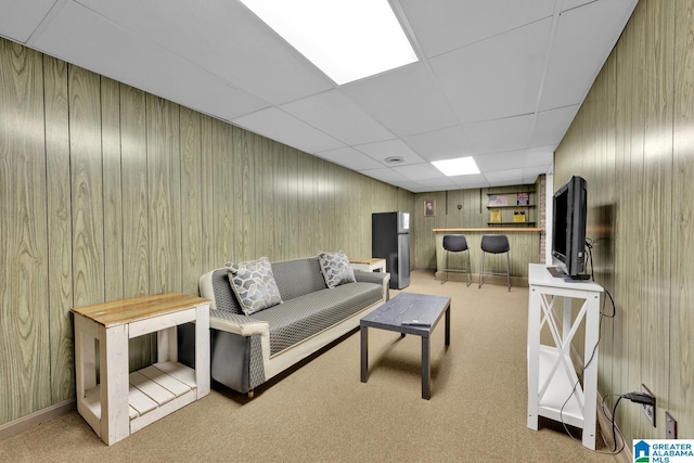 living room featuring a paneled ceiling, light colored carpet, and wooden walls