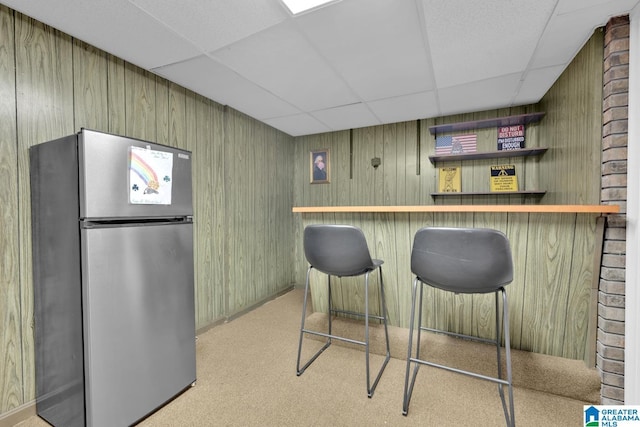 bar featuring stainless steel fridge and a paneled ceiling