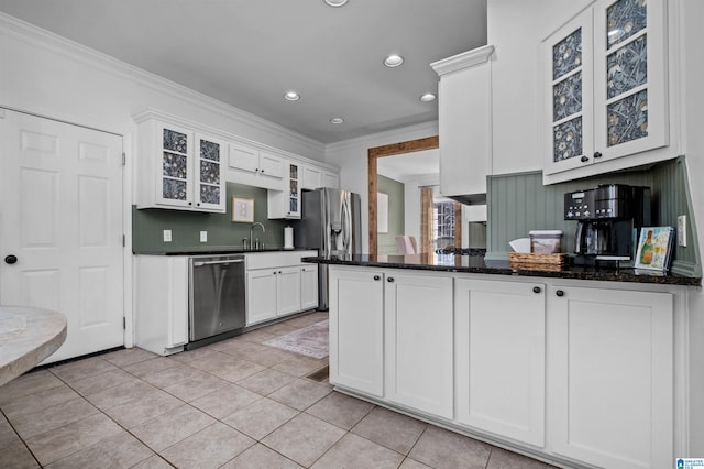 kitchen featuring light tile patterned floors, ornamental molding, appliances with stainless steel finishes, kitchen peninsula, and white cabinets