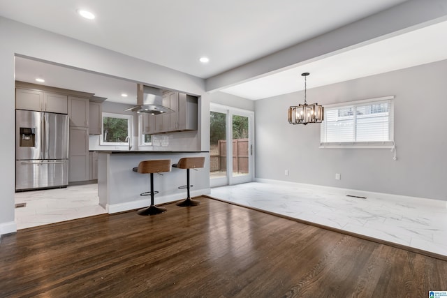 kitchen with island exhaust hood, a kitchen bar, light hardwood / wood-style floors, and stainless steel fridge with ice dispenser