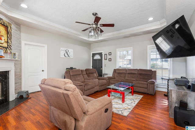 living room featuring a raised ceiling, dark hardwood / wood-style flooring, a textured ceiling, and a fireplace