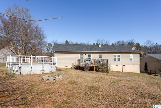 back of house with a fire pit, a yard, and a swimming pool side deck