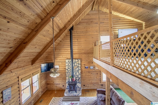 unfurnished living room featuring wooden ceiling, wood-type flooring, beam ceiling, and a wood stove