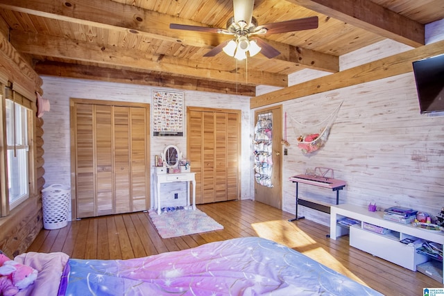 bedroom with wood ceiling, hardwood / wood-style flooring, ceiling fan, two closets, and beamed ceiling