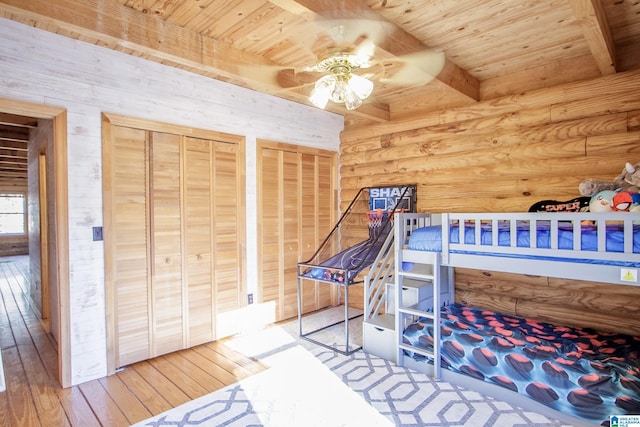 bedroom featuring wood ceiling, log walls, beam ceiling, and two closets