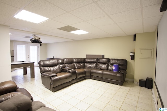 living room with french doors, a drop ceiling, and light tile patterned floors