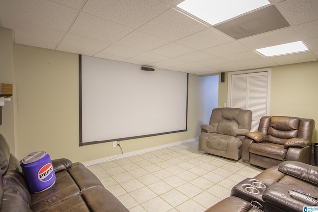 home theater with a paneled ceiling and light tile patterned flooring