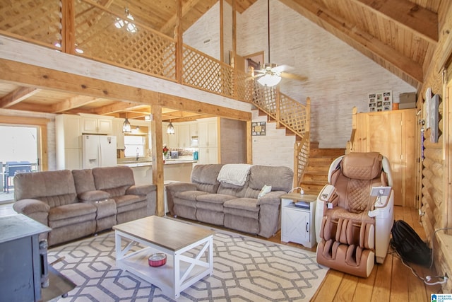 living room with wood ceiling, light hardwood / wood-style floors, beamed ceiling, and a high ceiling