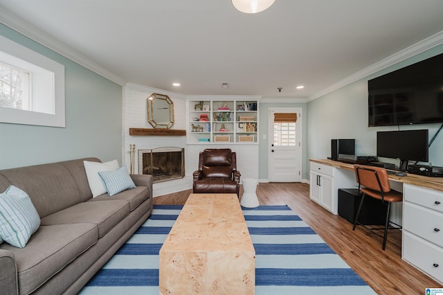 living room with ornamental molding, a brick fireplace, and light hardwood / wood-style flooring