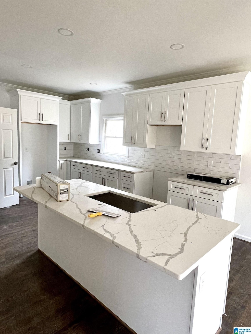 kitchen with light stone counters, tasteful backsplash, a center island, and white cabinets