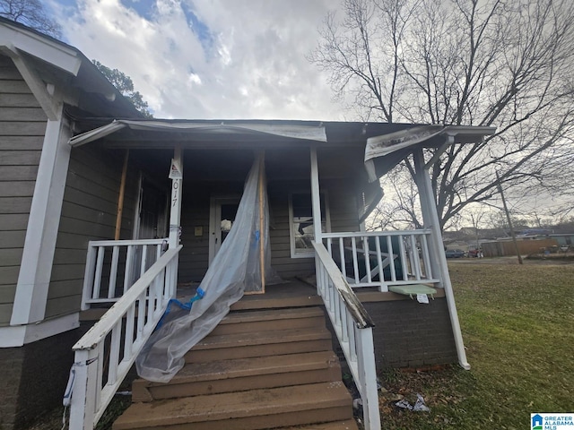 entrance to property with covered porch and a lawn