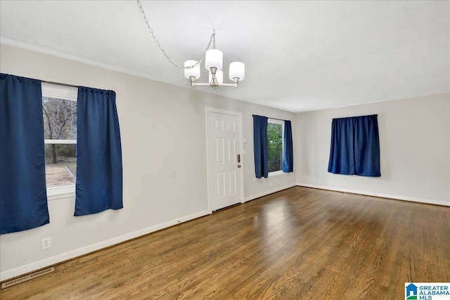 spare room with a notable chandelier and hardwood / wood-style flooring