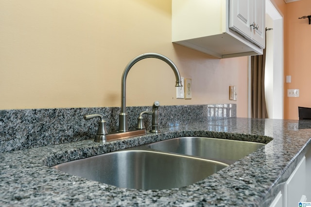 details featuring dark stone countertops, sink, and white cabinets