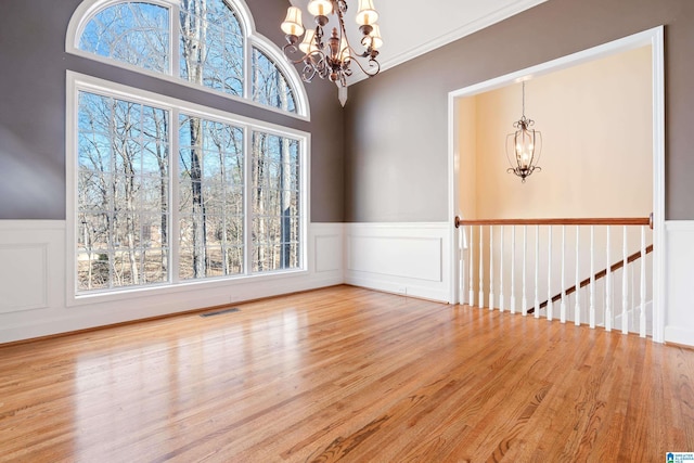 unfurnished room featuring plenty of natural light, a chandelier, and light wood-type flooring