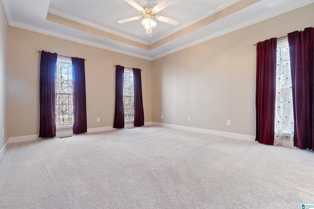 carpeted empty room with ceiling fan, ornamental molding, and a raised ceiling