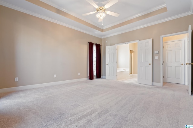 unfurnished bedroom featuring ensuite bath, ornamental molding, light colored carpet, and a raised ceiling