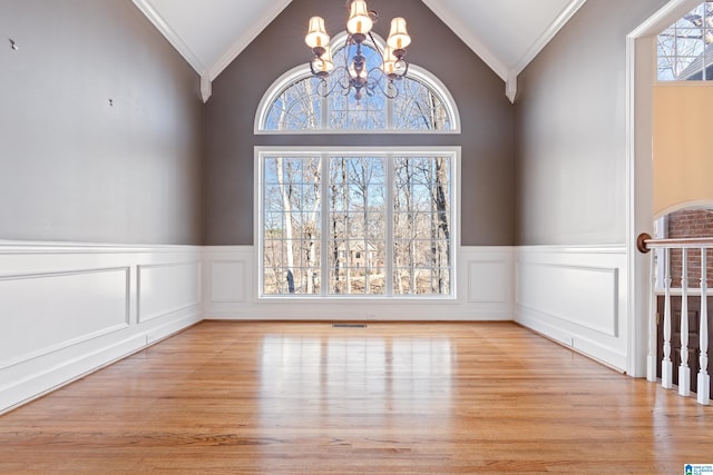 unfurnished dining area with light hardwood / wood-style floors, ornamental molding, a chandelier, and vaulted ceiling