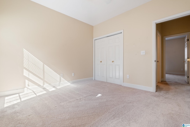 unfurnished bedroom featuring light colored carpet and a closet