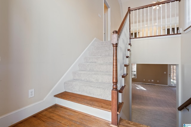 stairs featuring hardwood / wood-style flooring and a towering ceiling