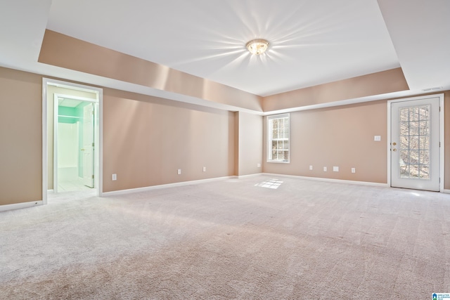 unfurnished room with a raised ceiling and carpet