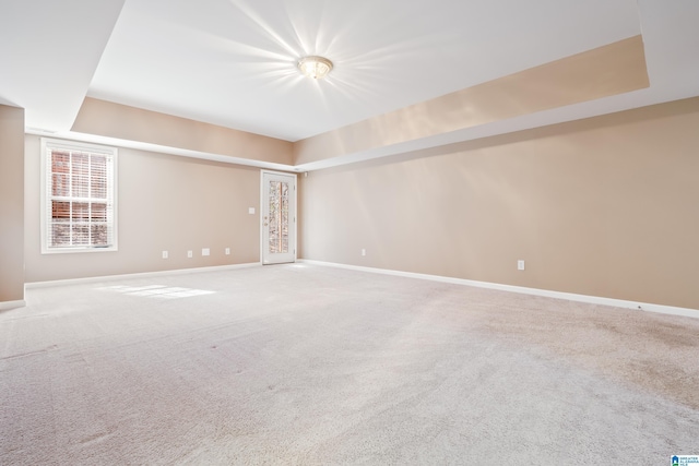 carpeted empty room with a raised ceiling