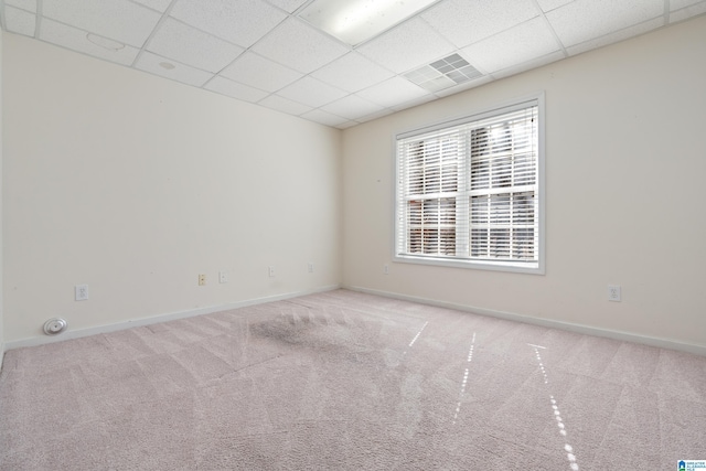 carpeted empty room featuring a drop ceiling