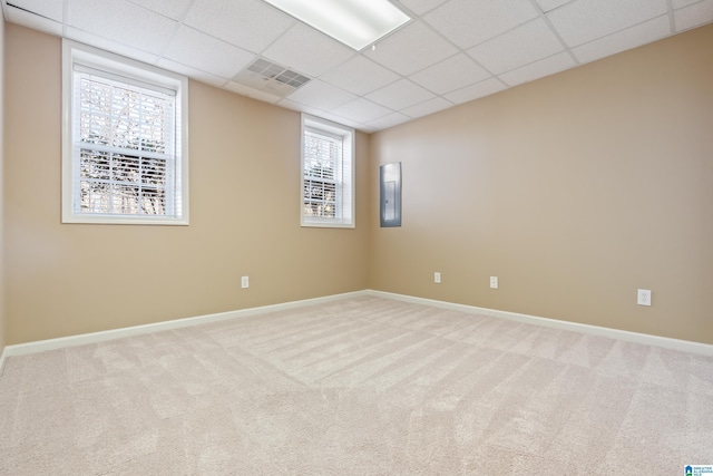 carpeted spare room featuring a paneled ceiling and electric panel