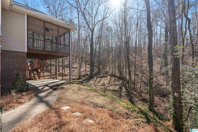 view of yard featuring ceiling fan and a sunroom