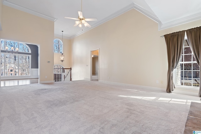 unfurnished living room with light carpet, crown molding, ceiling fan, and a towering ceiling