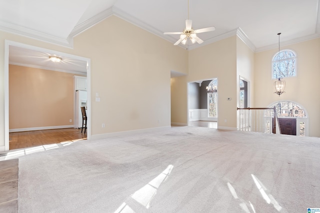 spare room with crown molding, a towering ceiling, ceiling fan with notable chandelier, and light carpet