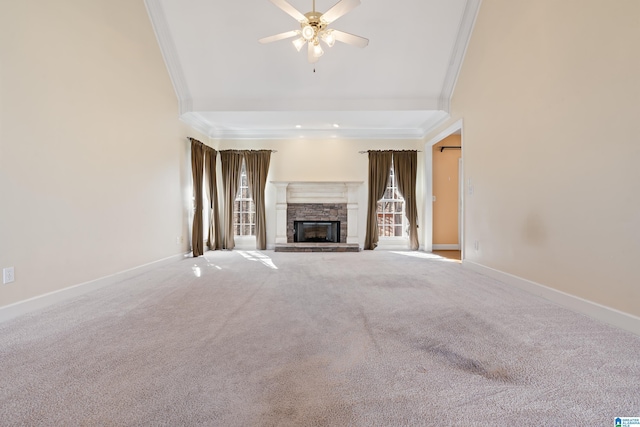 unfurnished living room featuring a stone fireplace, crown molding, carpet floors, a towering ceiling, and ceiling fan