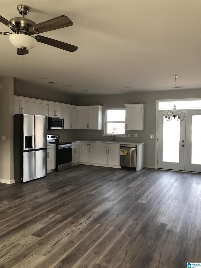 kitchen with dark wood-type flooring, stainless steel appliances, decorative light fixtures, and white cabinets