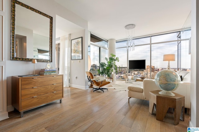 living room with expansive windows, a chandelier, and light wood-type flooring