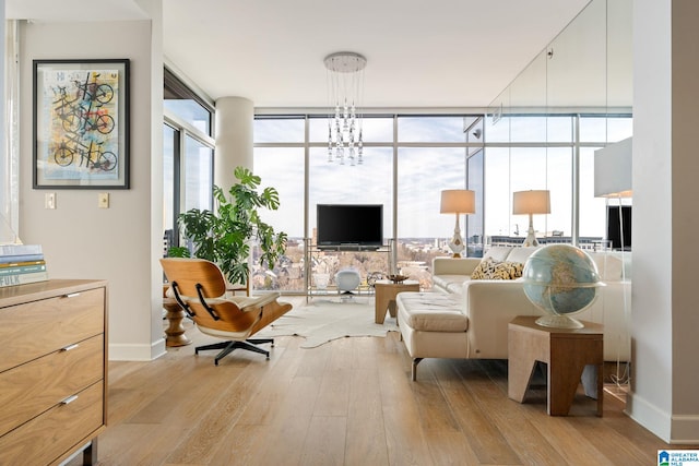 sitting room with floor to ceiling windows, a notable chandelier, and light hardwood / wood-style flooring