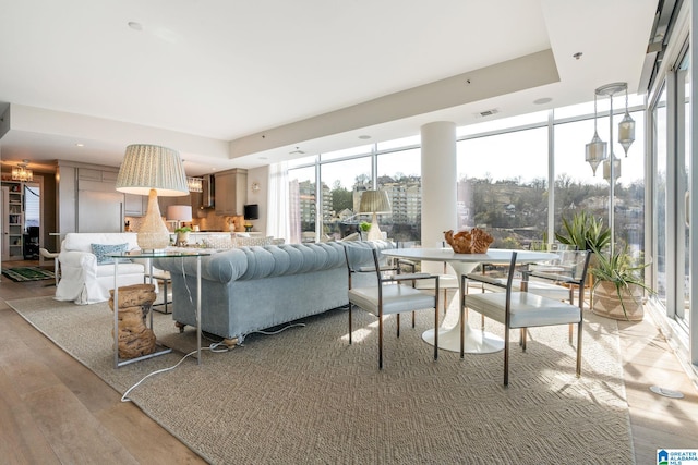 living room with expansive windows, light hardwood / wood-style floors, and a tray ceiling