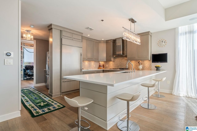 kitchen featuring pendant lighting, decorative backsplash, a kitchen breakfast bar, and wall chimney exhaust hood