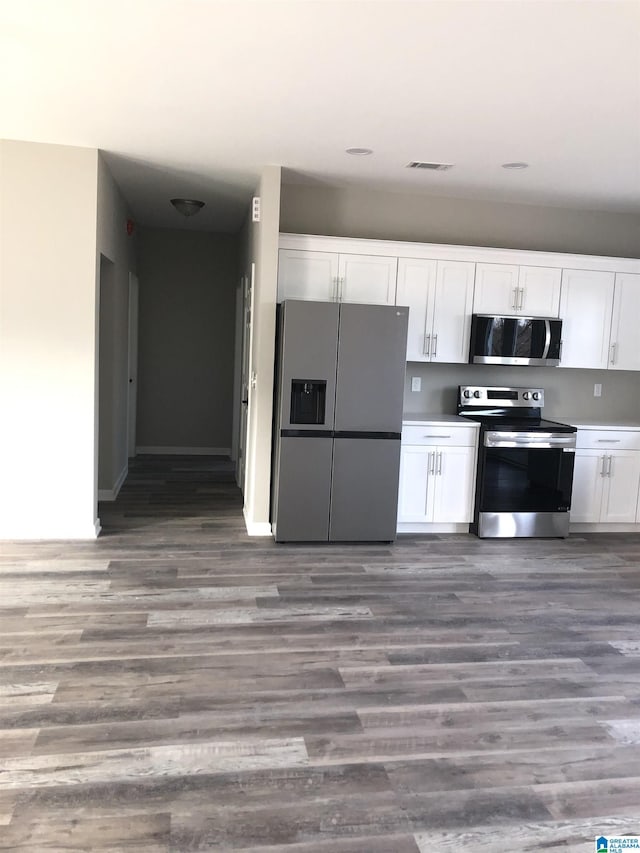 kitchen featuring dark hardwood / wood-style floors, white cabinets, and appliances with stainless steel finishes