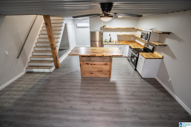 kitchen featuring appliances with stainless steel finishes, dark wood-type flooring, a wall mounted AC, and white cabinets