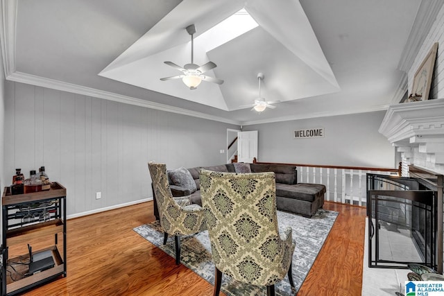 living room featuring crown molding, wood-type flooring, a raised ceiling, and ceiling fan