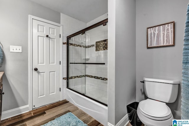 full bathroom with hardwood / wood-style flooring, vanity, toilet, and combined bath / shower with glass door