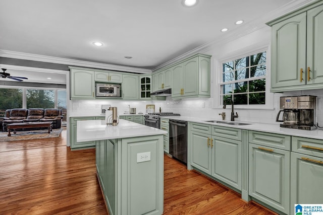 kitchen with a kitchen island, stainless steel microwave, dishwasher, sink, and green cabinetry