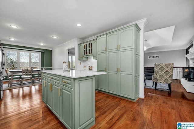 kitchen with ornamental molding, green cabinets, and a center island with sink